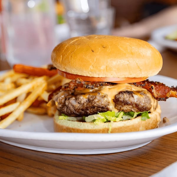 A juicy bacon cheeseburger with lettuce, tomato, and a side of golden french fries.
